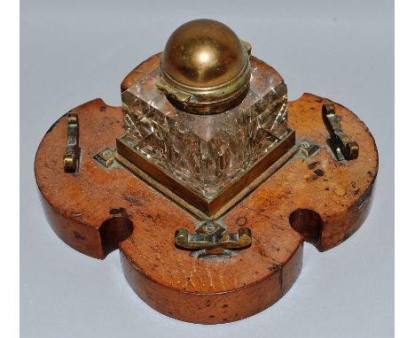 A GLASS INKWELL on a shaped wooden base.