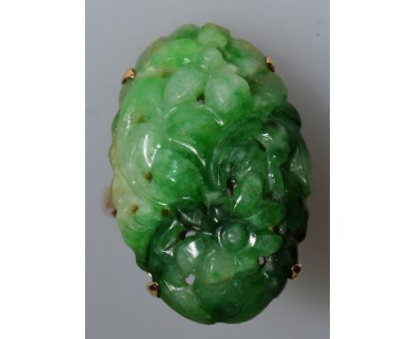 A SUPERB CHINESE CARVED GREEN JADE OVAL RING pierced and carved with flowers, set in yellow gold.