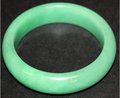 A CHINESE APPLE-GREEN JADE BANGLE, 3in diameter, the inner rim 2.25in diameter.