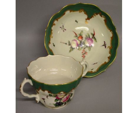 A GOOD 18TH CENTURY WORCESTER CHOCOLATE CUP AND STAND painted with fruit under an apple green border.