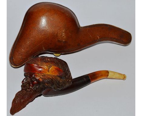 A 19TH CENTURY CARVED PIPE with amber mouth piece, the bowl carved as a bearded man, 6ins long, in a leather case.