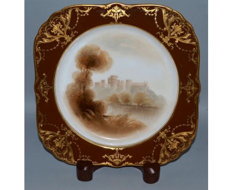 A ROYAL WORCESTER LOBED PLATE of square form painted with a castle scene on an unusual brown and raised gilt border signed by