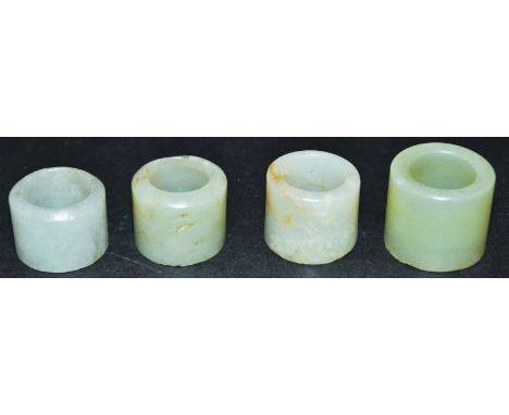 A GROUP OF FOUR CHINESE JADE ARCHER’S RINGS, of various sizes and mostly celadon tone, the largest 1in long x 1.25in diameter