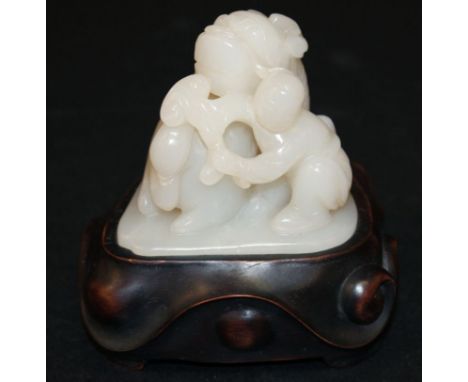 A CHINESE WHITE JADE CARVING OF A BOY & BUDDHISTIC LION, the kneeling boy holding a sprig of lingzhi, together with a fitted 