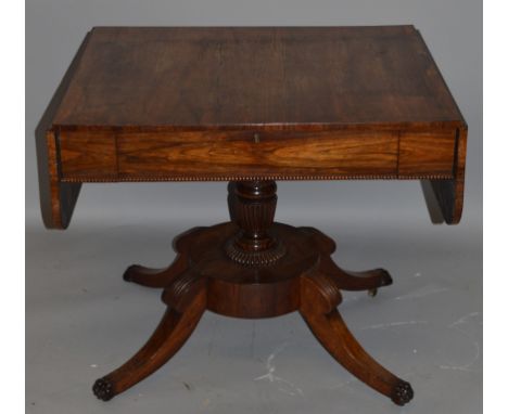 A LATE REGENCY ROSEWOOD SOFA TABLE with plain top, folding flaps and single frieze drawer on a centre column with shaped plat