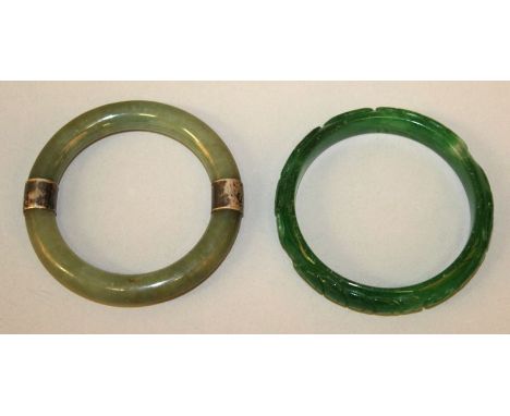  A CHINESE CELADON GREEN JADE BANGLE, with silver-metal sleeve attachments, 3in diameter, the inner rim 2.1in diameter; toget