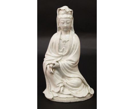 AN EARLY 20TH CENTURY CHINESE WHITE-GLAZED CRACKLEGLAZE FIGURE OF GUANYIN, seated in flowing robes and in traditional posture