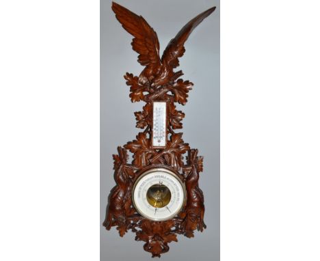 A VERY GOOD BLACK FOREST CARVED WOOD BAROMETER AND THERMOMETER, the case with an American eagle, wings fully stretched, carve