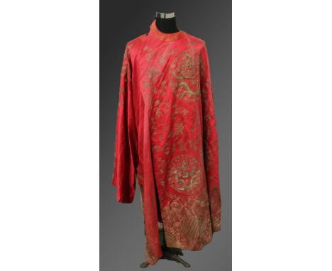 AN EARLY 20TH CENTURY CHINESE RED GROUND SILK ROBE, decorated in gilt thread with dragon roundels, bats, Shou symbols, cloud 