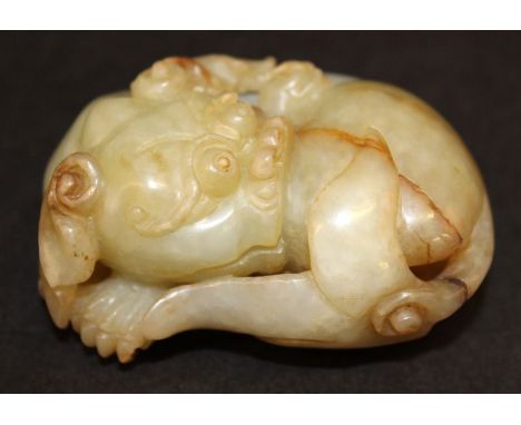 A GOOD QUALITY CHINESE JADE CARVING OF A RECUMBENT BUDDHISTIC LION, possibly 18th/19th Century, the predominantly celadon gre