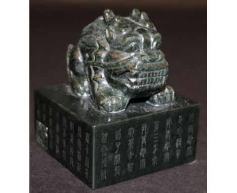 A CHINESE DARK GREEN JADE-LIKE SEAL, in the form of a mythical beast on a square-section plinth, the sides of the plinth deco