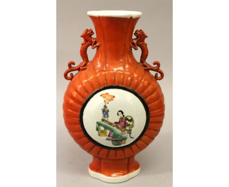  A CHINESE FAMILLE ROSE CORAL-GROUND PORCELAIN MOON FLASK, supported on a splayed foot, each side decorated with a panel of a