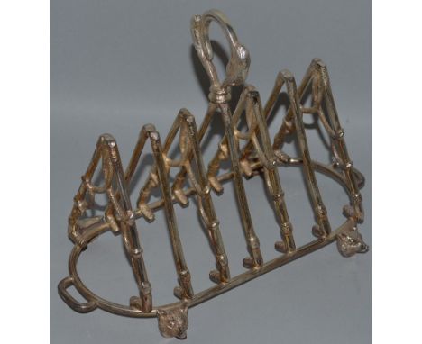 A “FOX HUNTING” SIX DIVISION TOAST RACK with seven crossed riding crops on four fox feet.