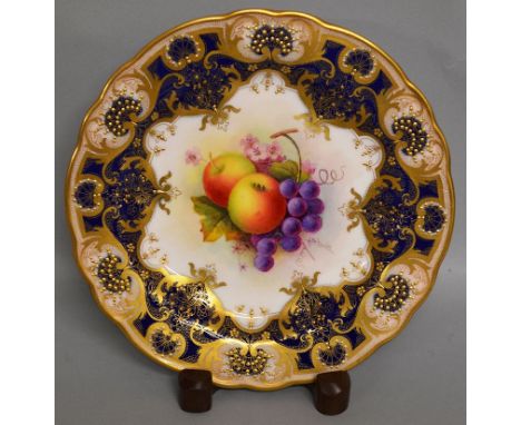 A ROYAL WORCESTER FINE PLATE PAINTED WITH FRUIT AND FLOWERS under a blue and gilt border and signed by ALBERT SHUCK date code