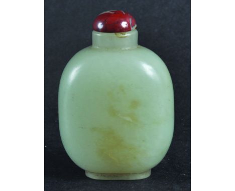  A CHINESE JADE SNUFF BOTTLE, with stopper, of flattened ovoid form, the pale green stone with darker inclusions, 2.3in high.