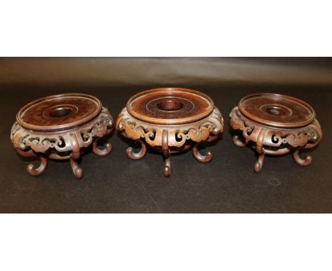 A GROUP OF THREE SIMILAR EARLY 20TH CENTURY CHINESE CARVED HARDWOOD VASE STANDS, each on scroll feet and with ruyi form pierc