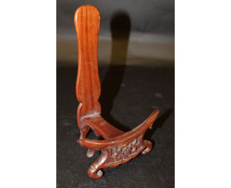 AN EARLY 20TH CENTURY CHINESE CARVED HARDWOOD PLATE STAND, supported on scroll feet and carved to the front with a foliate sp