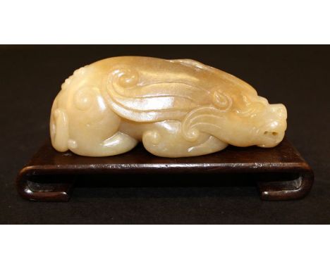 A CHINESE JADE-LIKE PAPERWEIGHT, in the form of a mythical beast, together with a wood stand, the paperweight 4in long. (2)