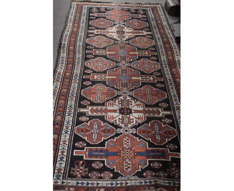 Middle Eastern wool floor rug decorated with large central panel with geometric design surrounded by a three-tier border, 290