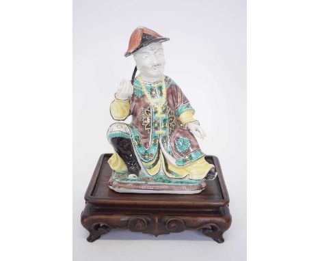 Chinese ceramic figure of a chinaman on wooden base with predominantly famille vert decoration on costume, 17cm high