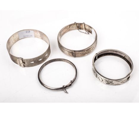 Four silver bangles. Including a late Victorian example part engraved with flowers, Chester 1887; an engine-turned 'belt' exa