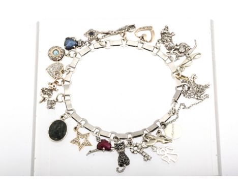 A 1940s French platinum bracelet in the manner of Boucheron hung with 21 various charms. The bracelet struck three times with