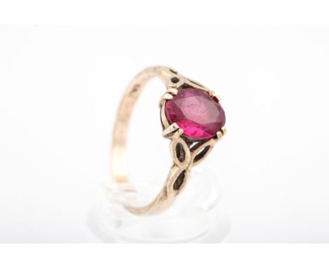 A 9ct gold and oval synthetic ruby single stone ring. The oval mixed-cut stone claw set between open elliptic-trefoil shoulde