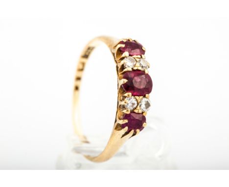 An early/mid-20th century gold, ruby and diamond dress ring. The graduated oval mixed-cut rubies spaced by pairs of small rou