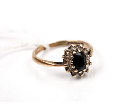 A vintage 9ct gold, sapphire and diamond oval cluster ring. Centred with an oval mixed-cut very dark-blue/black sapphire with