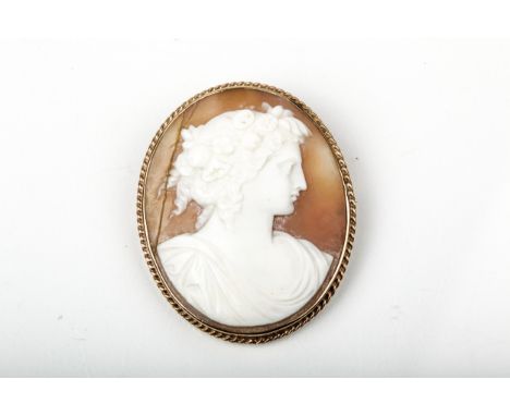 A vintage 9ct gold and oval shell cameo brooch. Depicting a neoclassical maiden wearing a floral garland in her hair, facing 