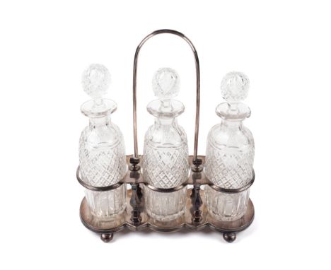 An early 20th century plated three bottle tantalus. with a central swing handle, the base of shaped outline on bun feet, With