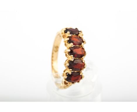 A vintage 9ct gold and garnet five stone ring. The oval mixed-cut garnets claw set on a textured gallery to a D-section shank