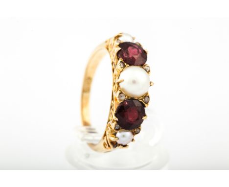 An early/mid-20th century gold, garnet and cultured-half-pearl five stone half-hoop ring. Cast in Victorian style, the three 