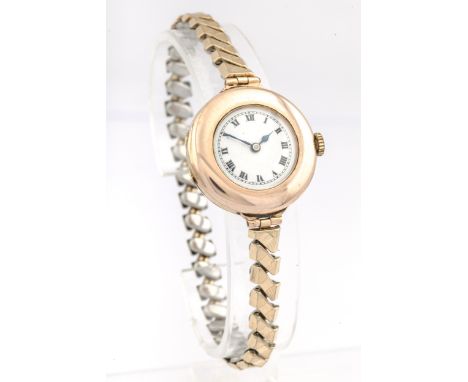 A lady's 9ct rose gold cased wristwatch, circa 1924. The white enamel dial with black Roman numerals, two piece hinged case w