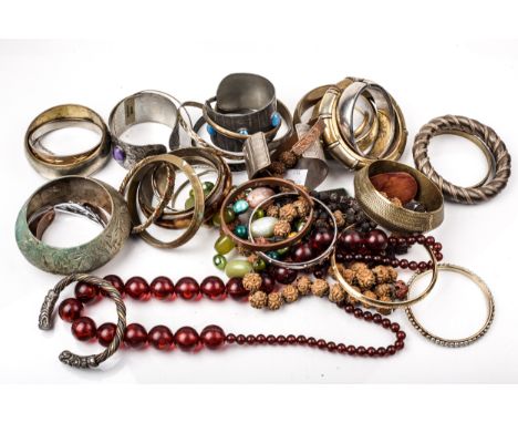 Thirty costume torque and slave bangles, an imitation red-amber bead necklace and other items. In many designs including a ro
