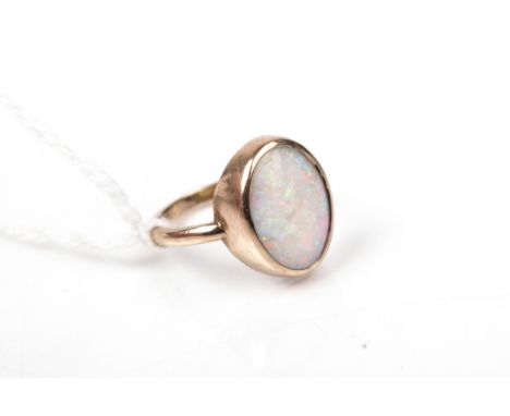 A vintage gold and opal single stone ring. The oval cabochon white opal, rub-over set on a tapering 'D' section shank, unmark