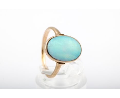 A vintage opal single stone ring. The oval cabochon white opal displays a play of mostly green colour, rub-over within a clos