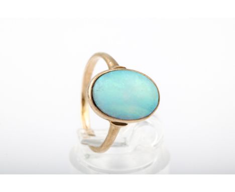 A vintage opal single stone ring. The oval cabochon white opal displays a play of mostly green colour, rub-over within a clos