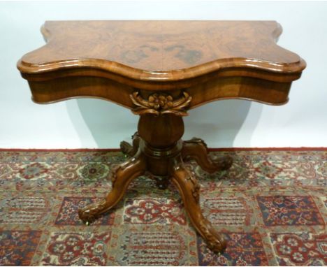 A Victorian Walnut Serpentine Card Table, the hinged top enclosing a baize lined interior above a carved frieze, raised upon 