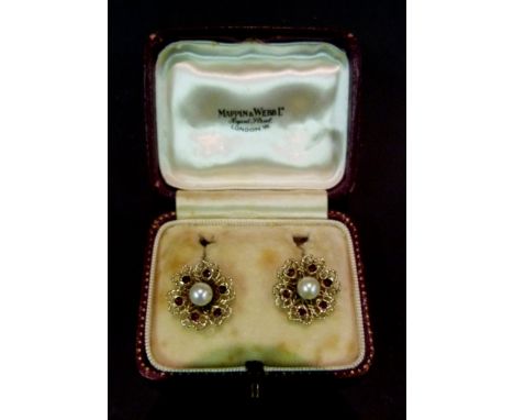 A Pair of Yellow Metal Pearl and Garnet Set Ear Studs, each set with a single pearl surrounded by six garnets within a pierce
