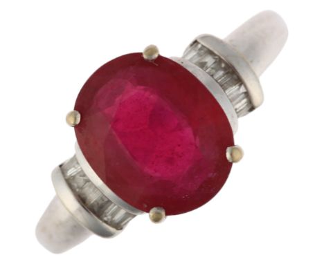 A modern 18ct white gold ruby and diamond dress ring, claw set with 2.7ct oval mixed-cut ruby flanked by baguette-cut diamond