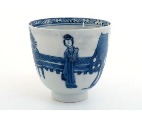 A Chinese porcelain blue and white wine cup, painted with ladies in a garden scape, mark to the base, Kangxi period, 7cm high