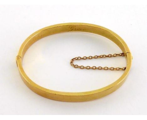 An 18 carat gold hinged bangle, the plain rectangular section solid band engraved to the inside edge 'Grace', with safety cha