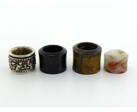 A group of four Chinese carved archer rings, one white metal with figures and marks, 3cm diam; one petrified wood carving of 
