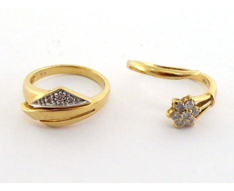 Two diamond rings, the first of cross over design terminating in a small daisy cluster of brilliants, the shank stamped '750'
