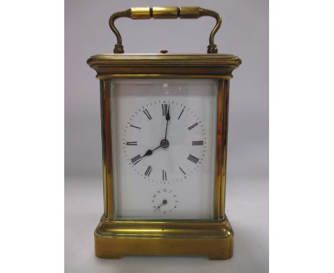 A brass carriage clock with white face and Roman numerals 