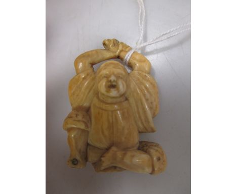 A 19th century ivory netsuke carved as a seated vendor stretching his arms above his head, 4cm (1.5 in.) high 