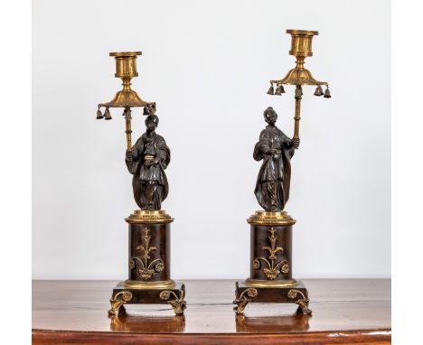 A pair of Regency gilt metal and bronze chinoiserie candlesticks, each with a standing robed Chinese figure holding a parasol