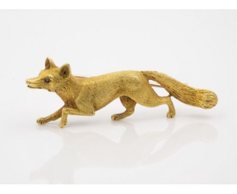 A 9ct gold and ruby fox brooch, realistically modelled, the eyes set with round cut rubies, 2 5/8in. (6.7cm.) long.