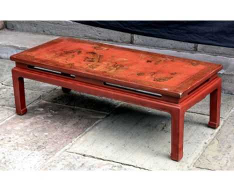 A Chinese style red japanned rectangular low table, late 19th / early 20th century, the top decorated in black and gilt with 